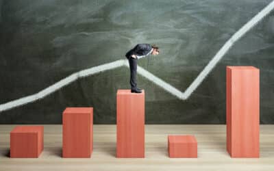 Businessman on red chart bars on chalkboard wall background crisis business and growth