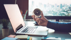 Businessman holding clock on computer laptop