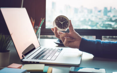 Businessman holding clock on computer laptop