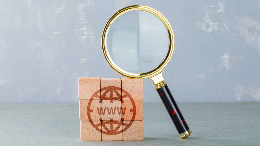 Conceptual of internet search with wooden blocks showing internet icon, magnifying glass side view