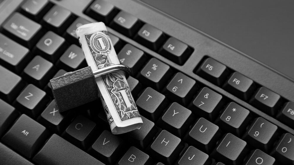 High angle shot of a lock around a dollar bill on a black laptop