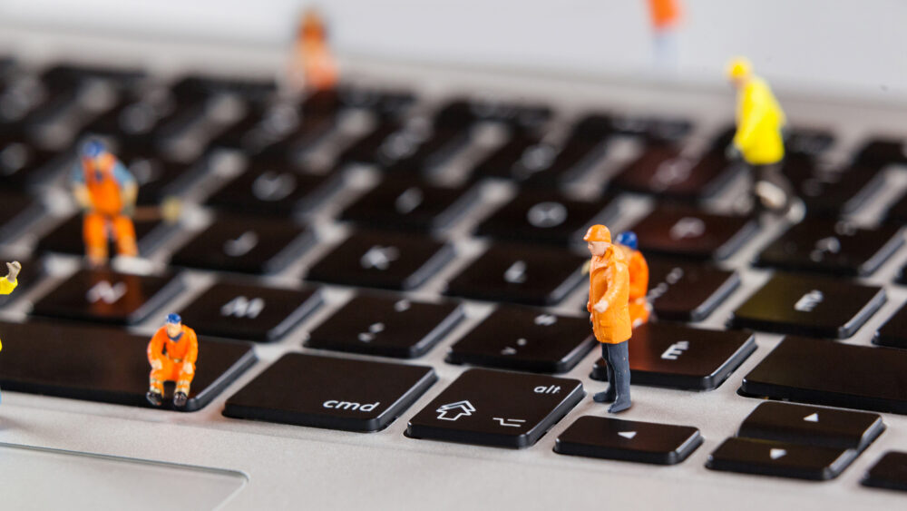 Miniature workmen repairing a laptop keyboard